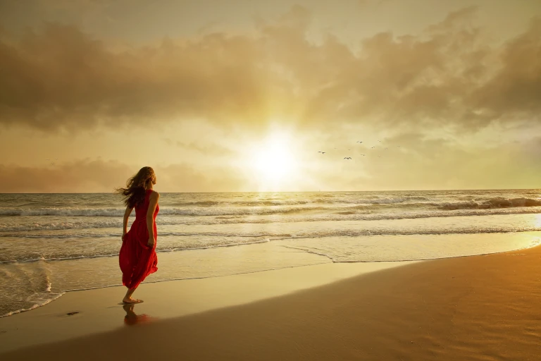 Woman in red dress on beach at sunset