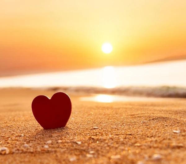 Red heart on beach at sunset